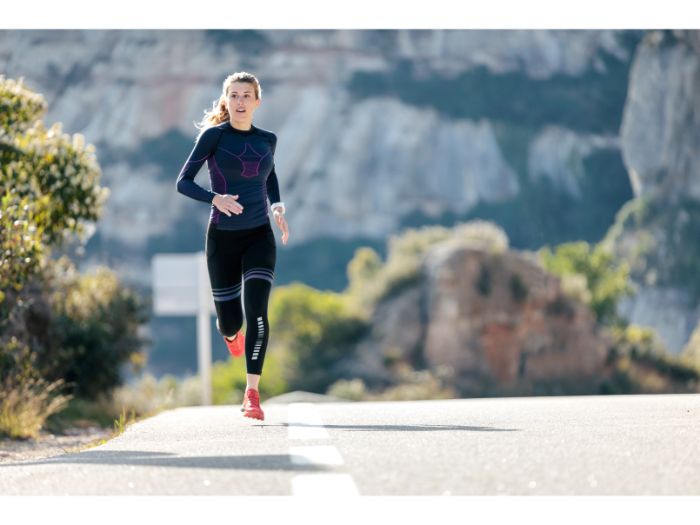 Sporty young woman running on mountain road in beautiful nature