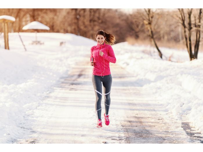 beautiful Caucasian woman in sportswear running on snowy weather 