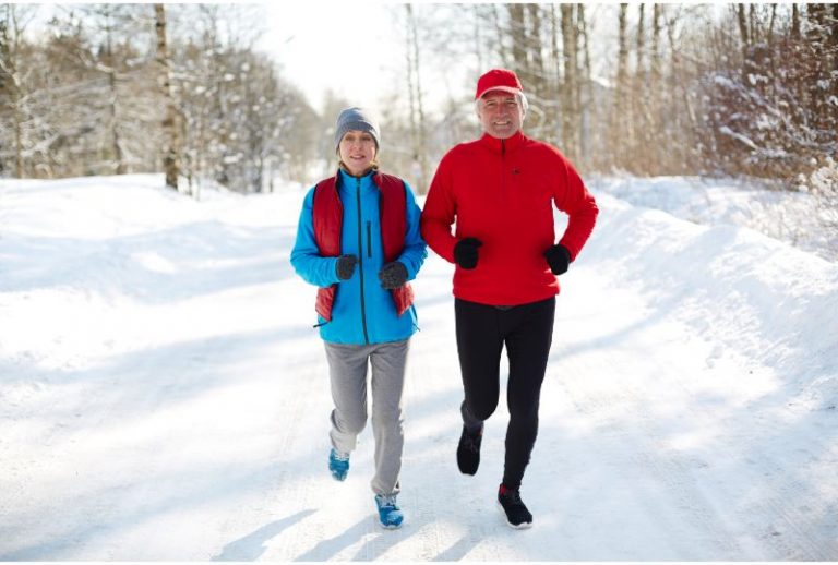Active seniors jogging down winter road