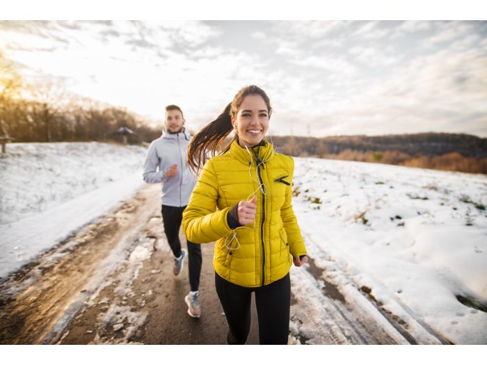girl jogging with her trainer on a snowy road in